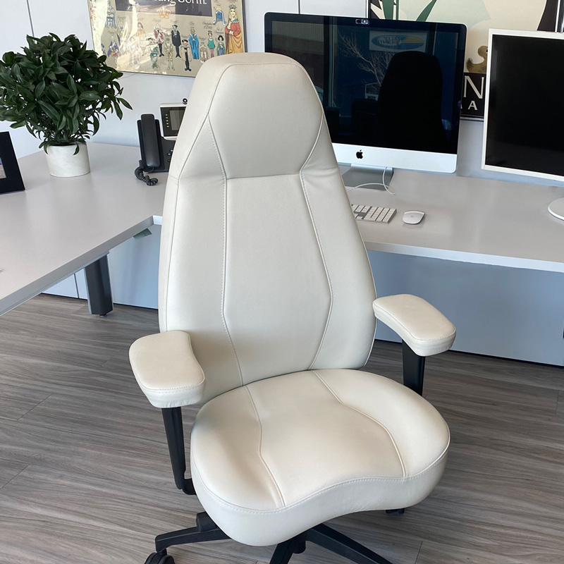 a 900 Legacy chair in white leather with a office desk behind it.