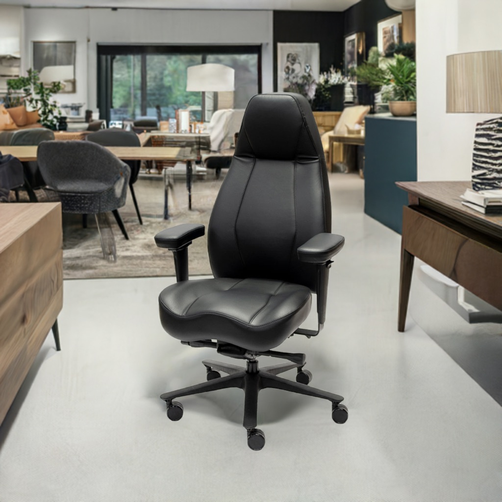 A black leather high-back ergonomic office chair with a contoured seat is featured in a modern, open-plan home office and living space.